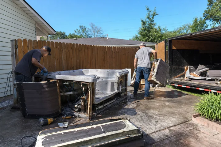Crew dismantling an old hot tub in a backyard